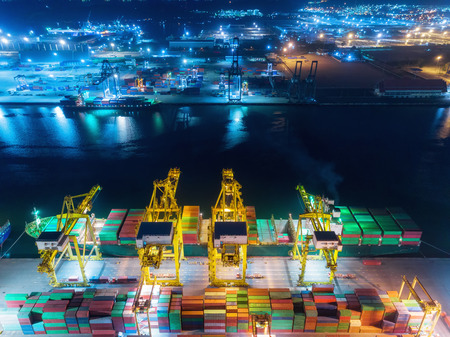 Aerial top view container ship at sea port and working crane bridge loading container for import...