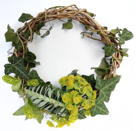 Top view of handmade rustic wreath with ivy leaves on white background. Creative composition. Seasons greetings card.の写真素材