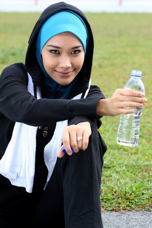 A muslim woman athlete holding a bottle of mineral waterの写真素材