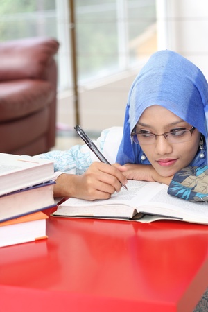 A muslim woman reading a book while looking at the book on the tableの写真素材