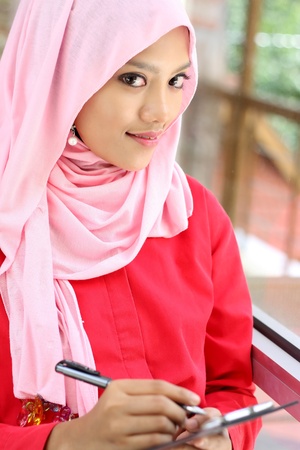 A young muslim woman holding report file while looking at cameraの写真素材