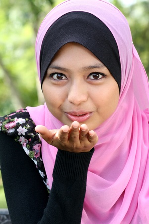 Portrait of cute young muslim female blowing kissの写真素材
