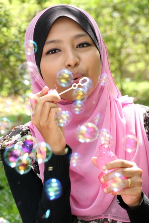 Young  pretty muslim girl inflating colorful soap bubbles の写真素材