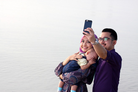 Beautiful family at beach making a self portrait with a mobile phoneの写真素材