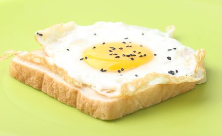 Fried egg on a slice of wholemeal bread with green plateの写真素材