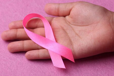 Pink ribbon on hand with pink background. Breast cancer awareness conceptの写真素材