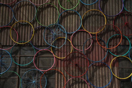 Colorful bicycle wheel on the wall of the old house in Thailandの写真素材