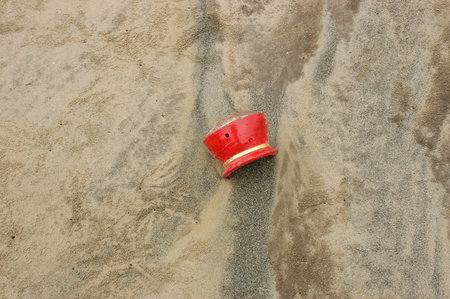 A red bucket on the sand of a beach, closeup of photoの写真素材