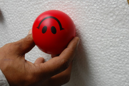 Red ball with a smiley face on a white wall background.の写真素材