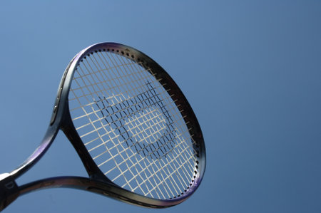 Tennis racket on a blue sky background, closeup of photoの写真素材
