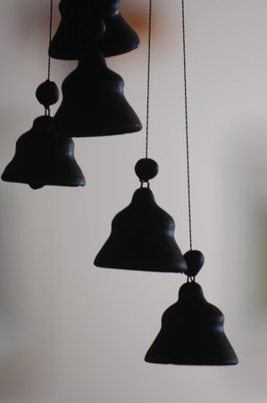 black bell hanging on the ceiling in the room with light and shadowの写真素材