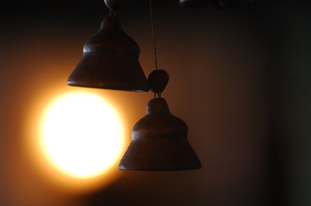 Old bell in a dark room with a light coming through it.の写真素材