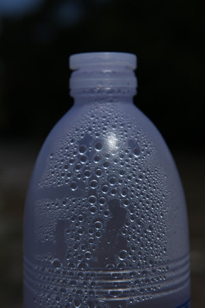 Plastic bottle with water drops on the beach, close-up