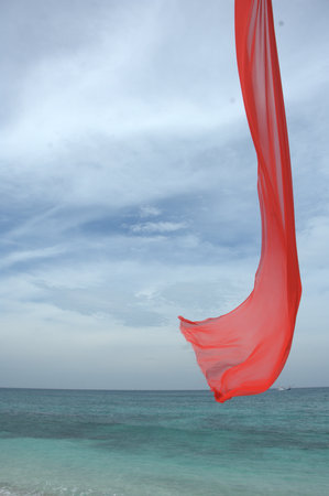red cloth flying in the wind on the beach with blue sky backgroundの写真素材
