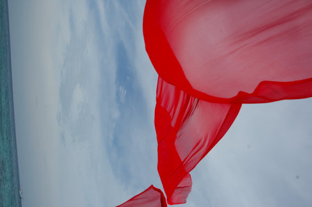 Red fabric on blue sky background. Red cloth flying in the windの写真素材