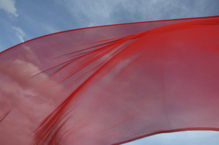 Red cloth waving in the wind on a background of blue sky.の写真素材