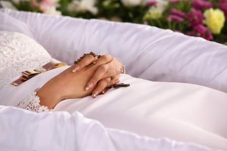 Bride's hands with wedding rings lying on a white pillow surrounded by flowersの写真素材