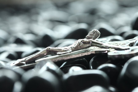 Close-up of silver crucifix on black stones. Selective focus.の写真素材
