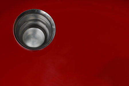 A closeup shot of a stainless steel sink on a red background