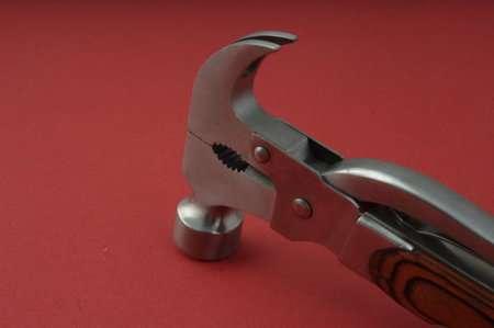 Stainless steel pipe wrench on a red background, close-up
