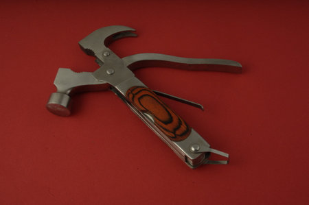 A close up shot of a multitool isolated on a red background