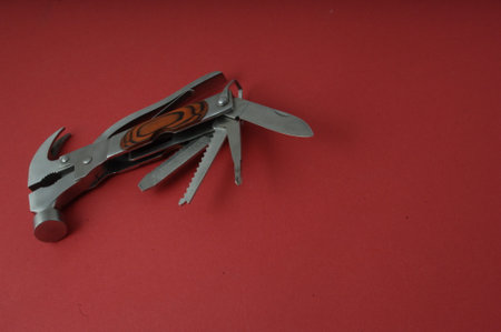 Multifunctional tool on a red background, close-up
