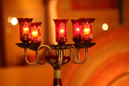 Candle holder in the shape of a heart with burning candles on a blurred backgroundの写真素材