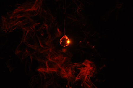 Incandescent light bulb on a black background with red smoke.