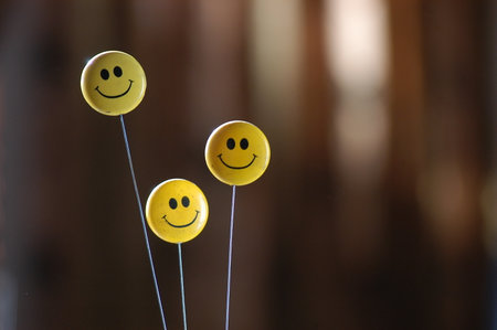 Smiling yellow emoticons on a stick on a blurred background.の写真素材