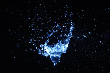 Water splashes out of a wine glass on a black background.の写真素材