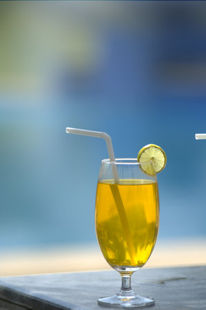 A glass of orange juice with a straw and a slice of lemon.