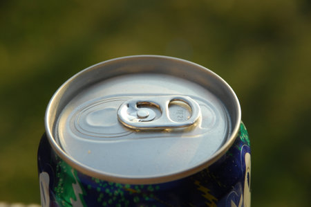 Close up of a can of beer on a green grass background.
