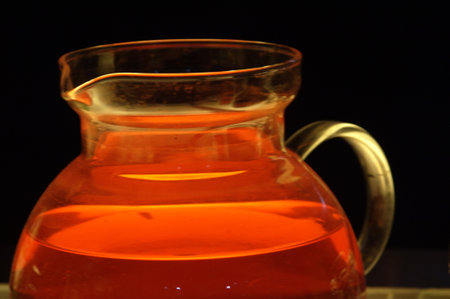 Orange tea in a glass decanter on a black background.の写真素材