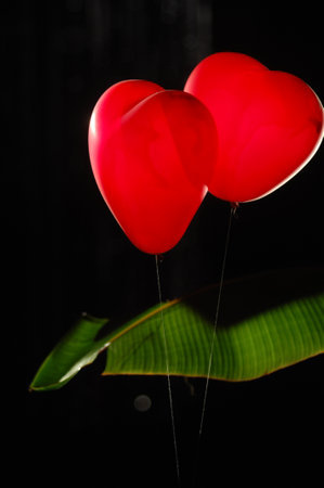 Red heart shaped balloons on black background. Valentine's day concept.の写真素材
