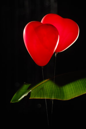 Red heart shaped balloon on black background. Valentine's day concept.の写真素材