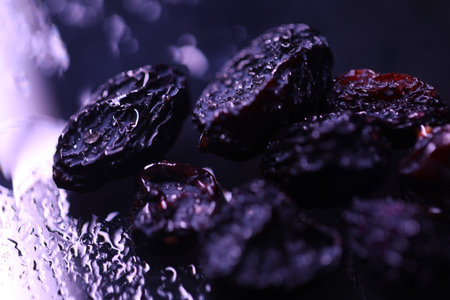 Black raisins on a dark background with water drops close upの写真素材