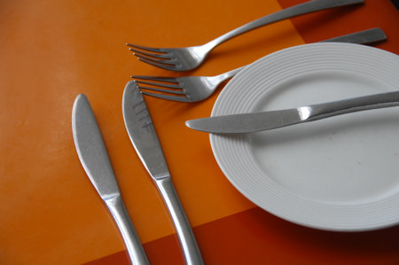 Knife, fork and plate on orange background. Table setting.の写真素材