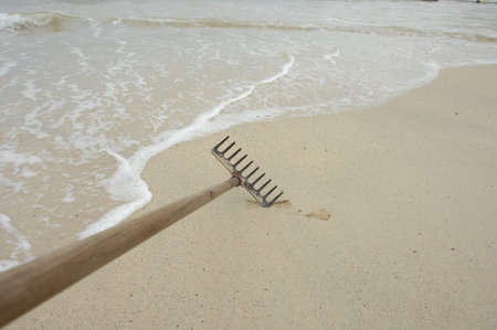 Garden rake on the sandy beach with waves and white sand.の写真素材