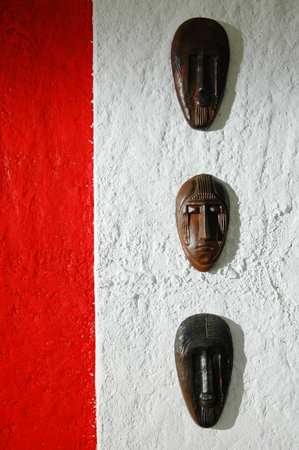 Wooden masks on a white wall with red and white stripes.の写真素材