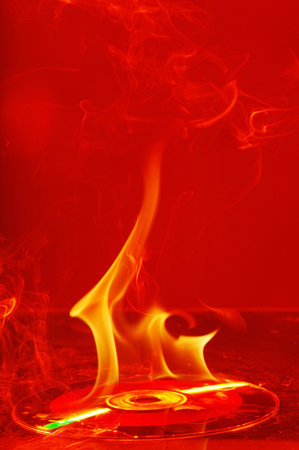 Burning vinyl record on a red background. Close-up.