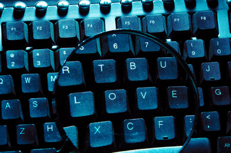 Computer keyboard with a magnifying glass. Blue toned image.の写真素材
