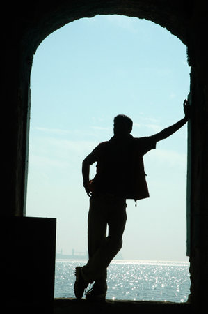 Silhouette of a man standing in a doorway overlooking the seaの写真素材