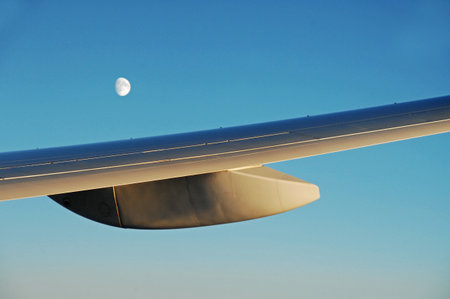 View of the wing of an airplane with the moon in the background