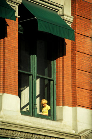 The window of a house with a doll in the foreground and brick wall