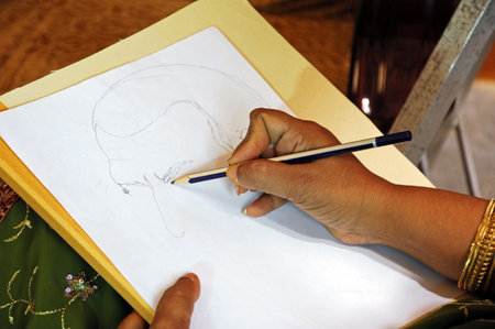 An image of a hand drawing a sketch on a wooden table.
