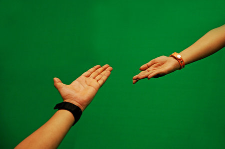 Man and woman hands reaching for each other on a green background.の写真素材