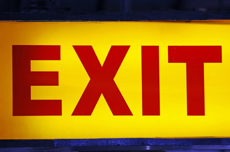 Exit sign in yellow and red on a black background. Close-up.
