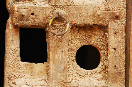 Old rusty door with a hole in the wall, closeup of photoの写真素材