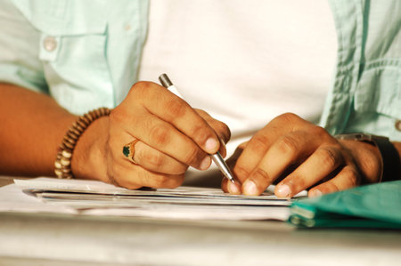 Close-up of a man's hands writing with a pen.の写真素材