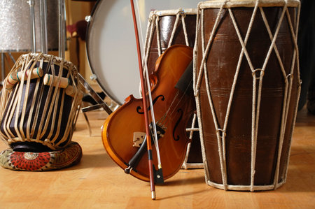 Close-up of a violin and drum set on a wooden floorの写真素材